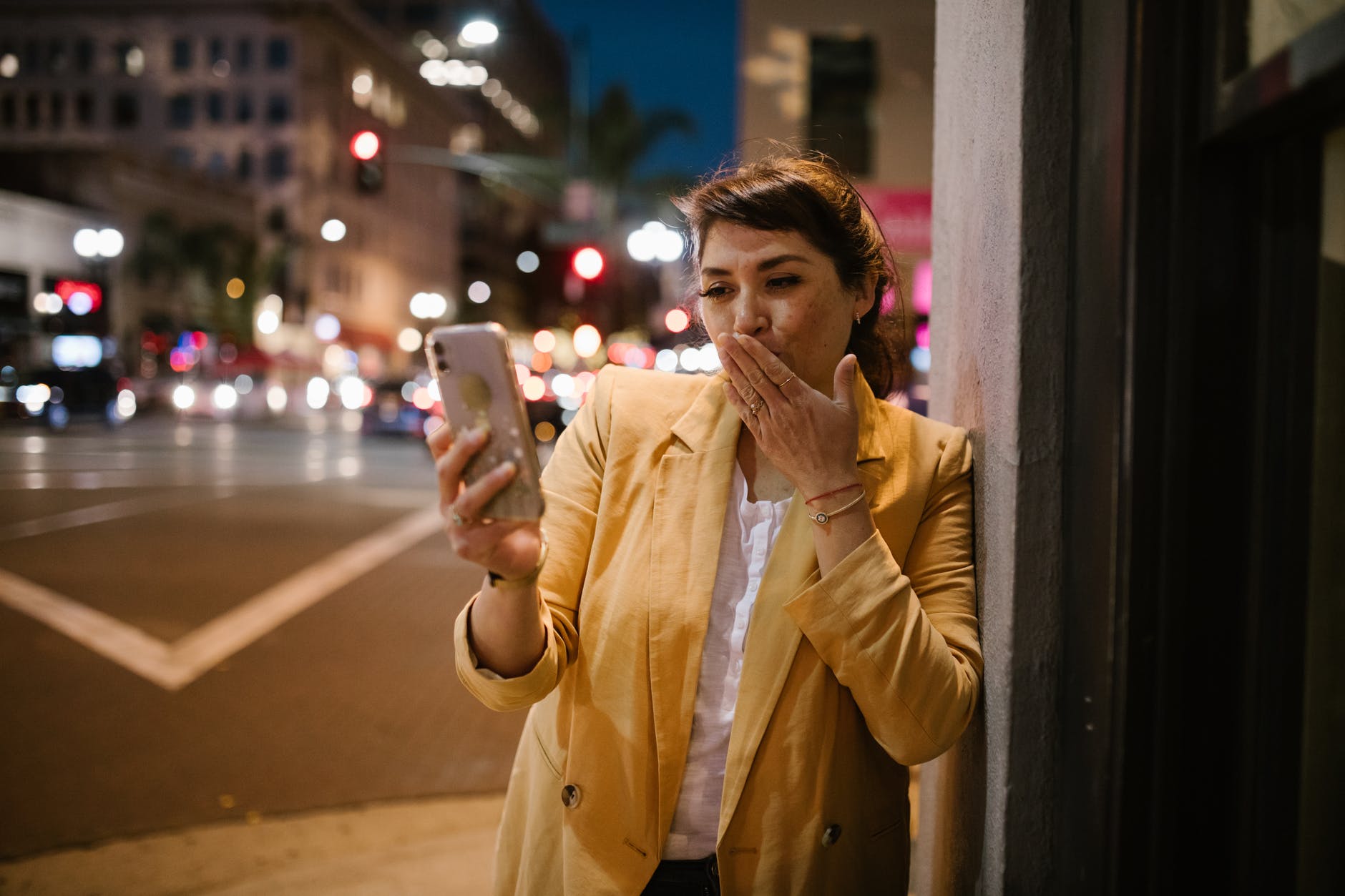 woman in brown coat holding white smartphone